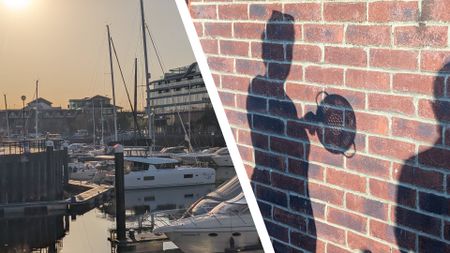 Boats in a marina at sundown during the 2026 solar eclipse, alongside a shadow on a wall of a person holding a colander