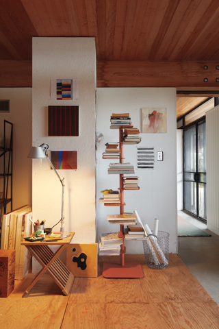 A study space with a desk, an oversized table lamp, and a tall bookshelf
