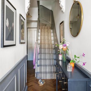 hallway with navy sideboard and stairway with striped runner