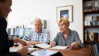 An elderly couple talking with a financial adviser.