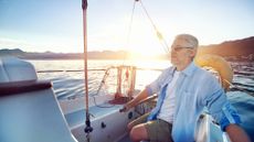 Senior man sailing boat at sunrise