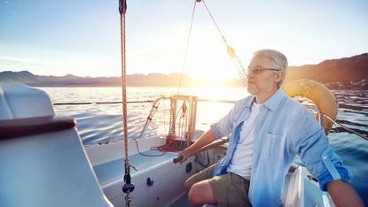 Senior man sailing boat at sunrise