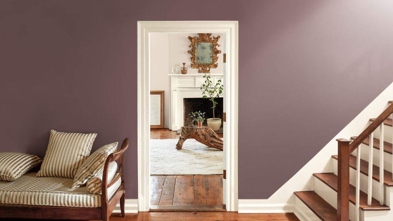 entryway with purple walls, staircase, and doorway leading into neutral living space with fireplace