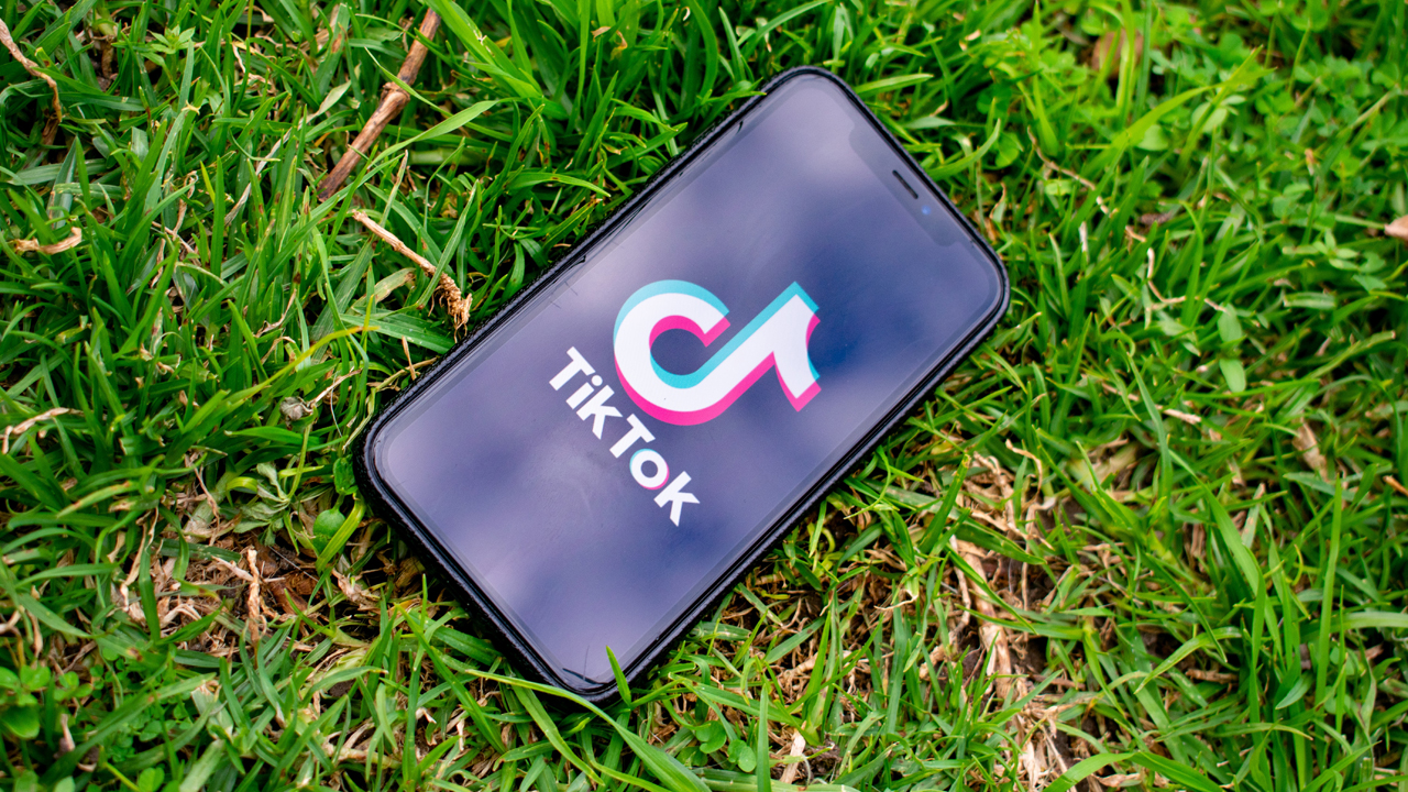 Mobile phone displaying the TikTok logo laying on green grass
