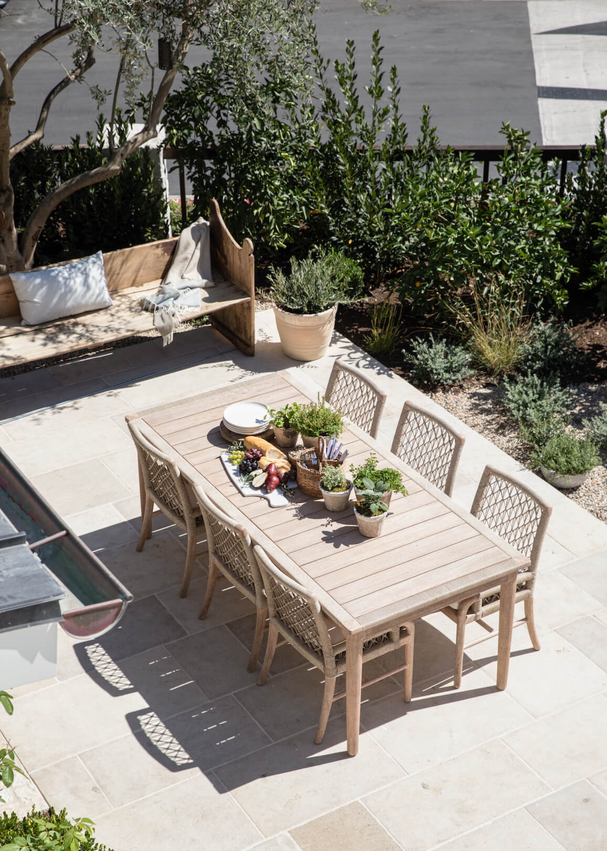Outdoor dining table with rustic potted herbs and dining chairs placed around the table