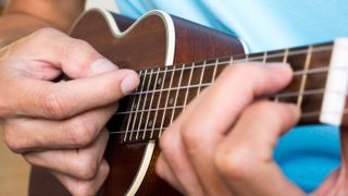 Close-up image of hands on a ukulele fretboard