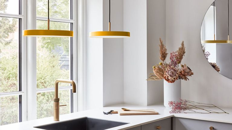 Kitchen sink detail with duo of yellow disk design pendants suspended above
