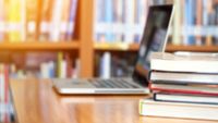 Book stack and laptop in library with blurred focus for background