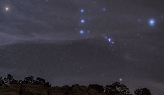 night sky showing three very bright stars in a line forming orions belt.