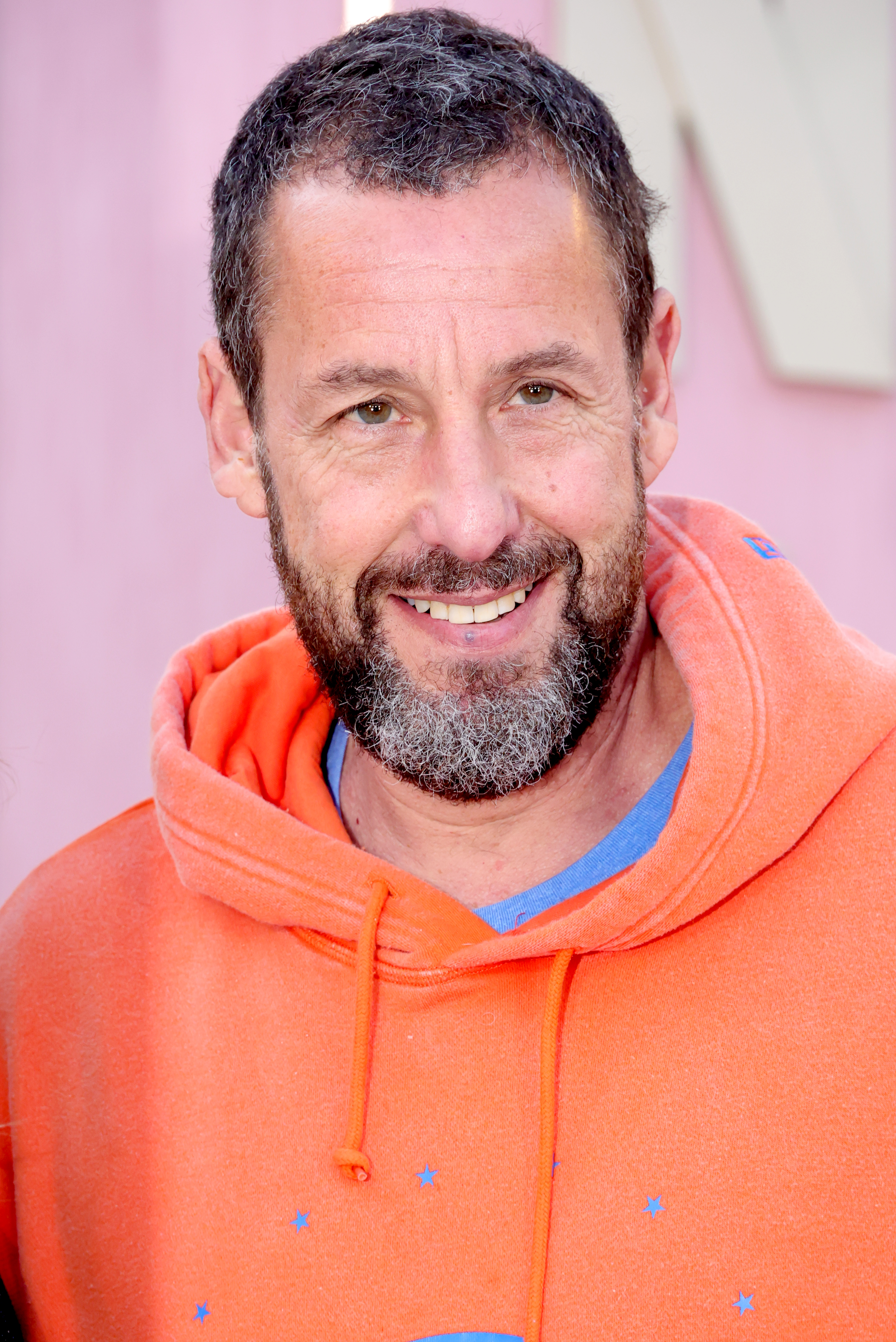 Adam Sandler in an orange hoodie