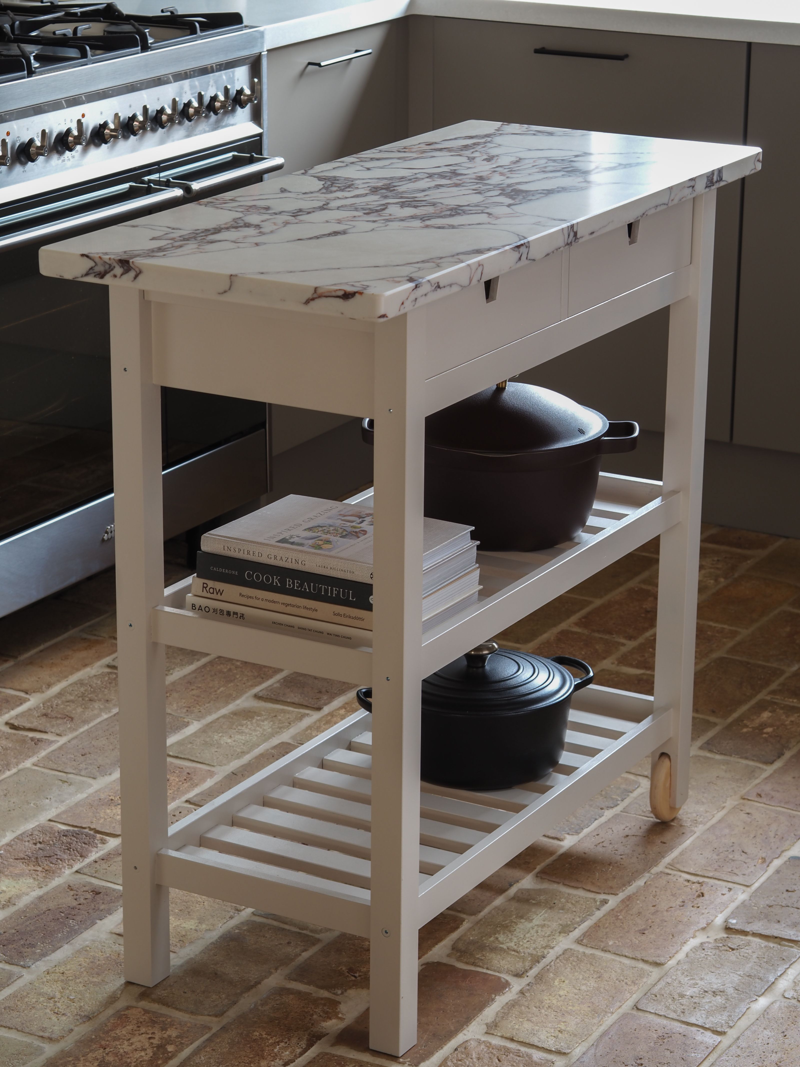 a small ikea kitchen island in a kitchen with a brick floor and an oven in the background