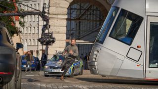 Un plan des coulisses de Sierra Six, le personnage de Ryan Gosling, passant en courant devant un tramway tandis qu'une caméra le filme dans The Gray Man.