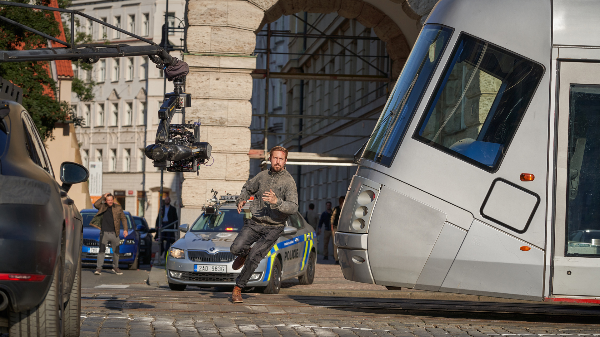 A behind-the-scenes shot of Ryan Gosling's Sierra Six running past a tram while a camera fills him in The Gray Man