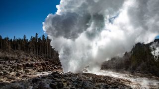 Yellowstone's Steamboat Geyser sends a cloud of water spray over the surrounding landscape.