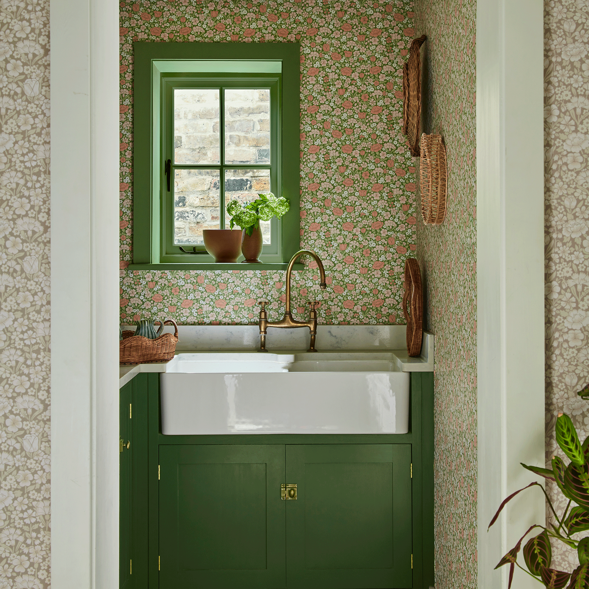 Utility room with ditsy wallpaper and green cabinetry