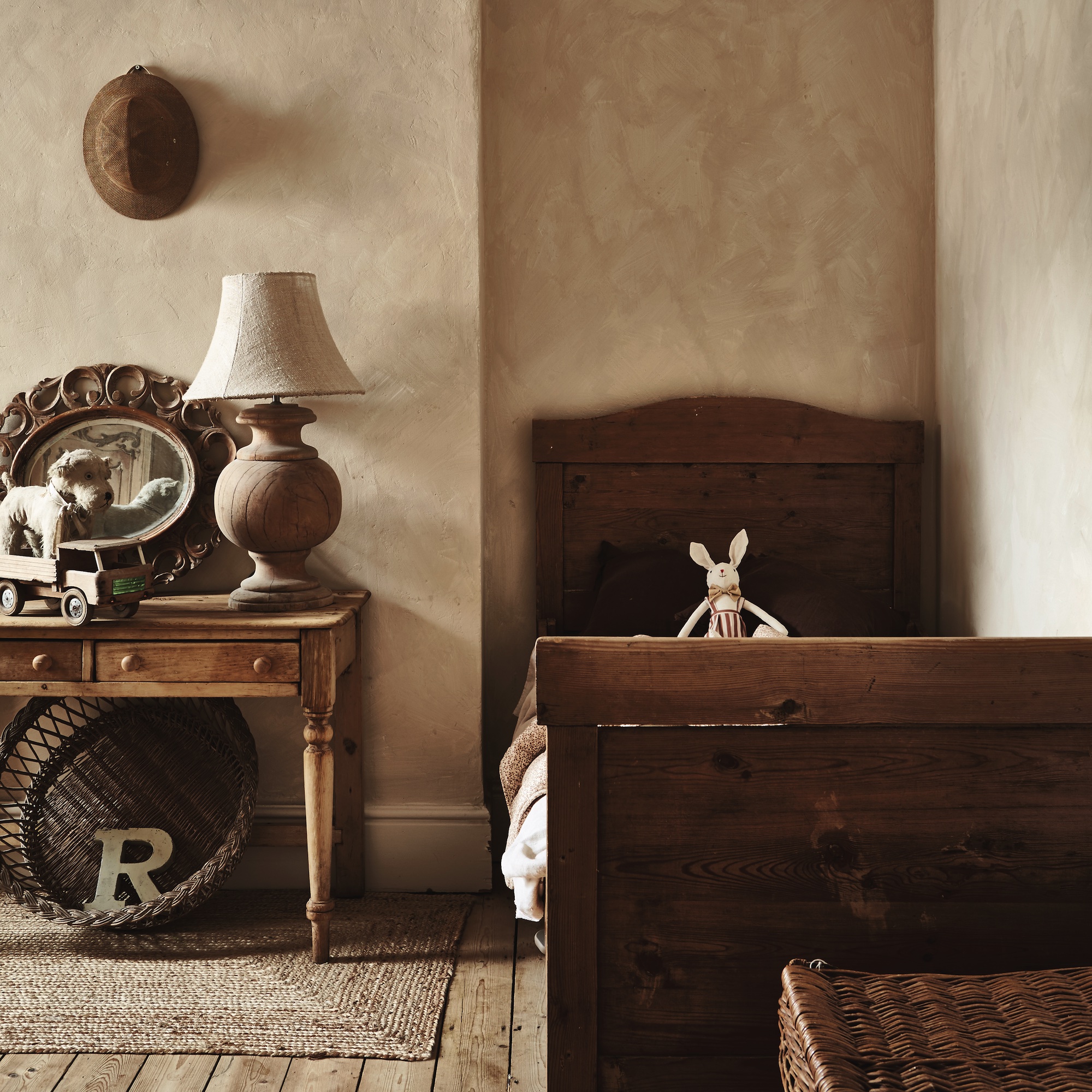 child's bedroom with narrow antique bed and desk with vintage wooden toys and lamp