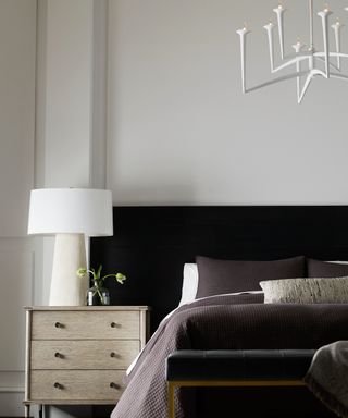 bedroom with large white shaded bedside light on bedside table and modern white pendant light above bed