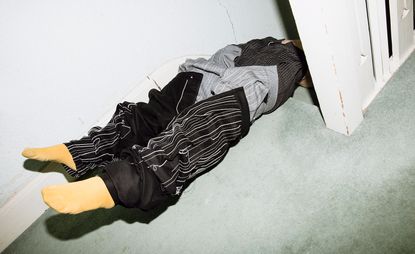Photography portfolio, titled ‘The Artist is Incognito’, captures a faceless model lying at the top of a carpeted staircase wearing three pairs of trousers and yellow socks 