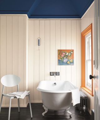 White panelled wall in bathroom with blue ceiling and wooden floor