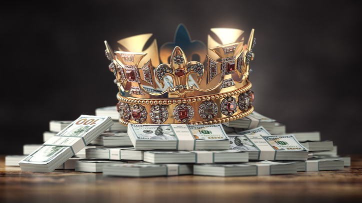 a jeweled crown placed on top of stacks of hundred-dollar bills