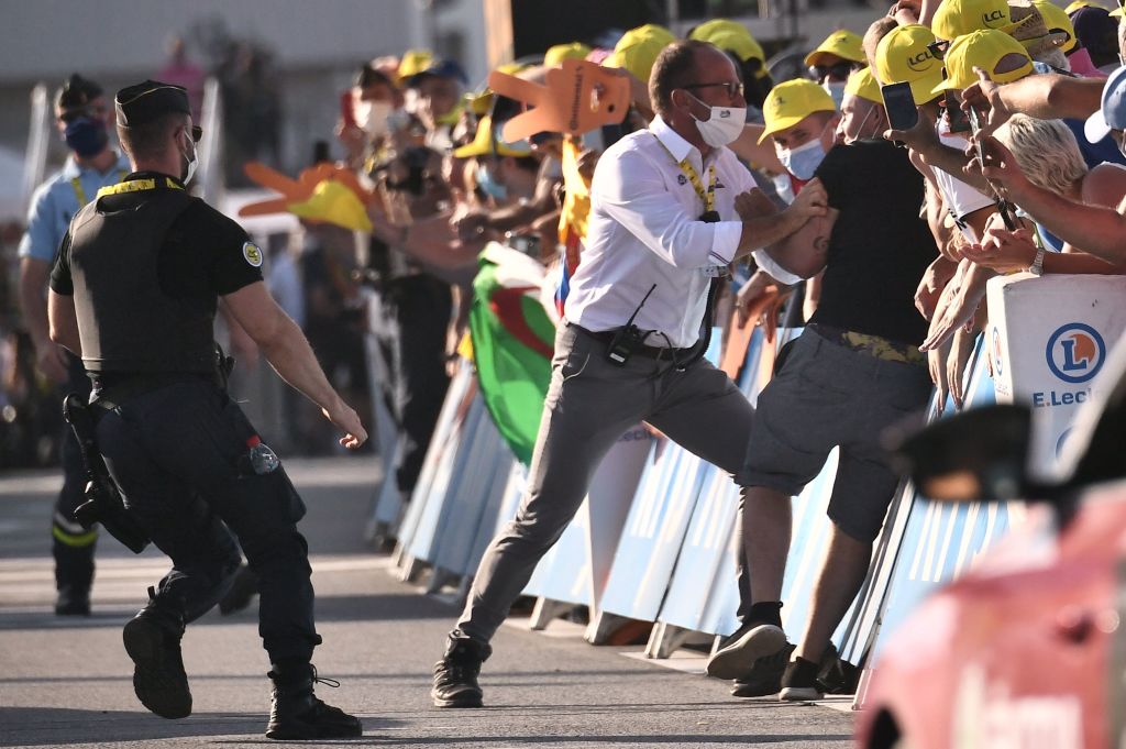 A man who jumped over the barriers is detained by a staff member at the end of the 18th stage of the 107th edition of the Tour de France cycling race 168 km between Meribel and La Roche sur Foron on September 17 2020 Photo by Marco Bertorello AFP Photo by MARCO BERTORELLOAFP via Getty Images
