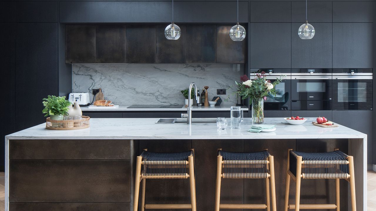 Kitchen with black cabinetry, wooden floors, large island and bar stools