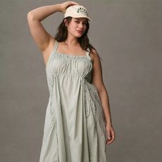 model wears pale green dress sneakers with socks and a baseball hat 