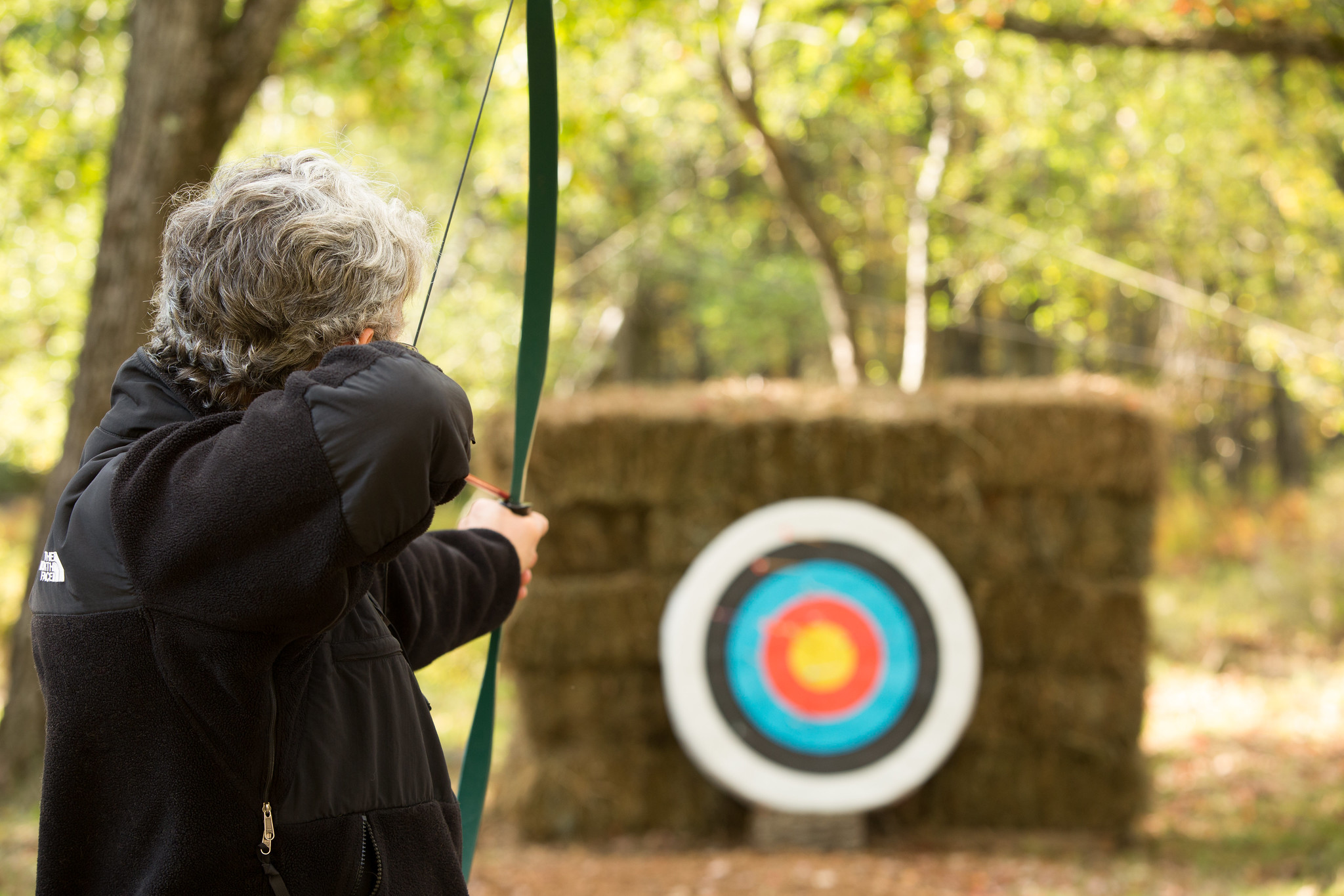 A woman aims a bow and arrow toward an archery target at Woodloch Resort