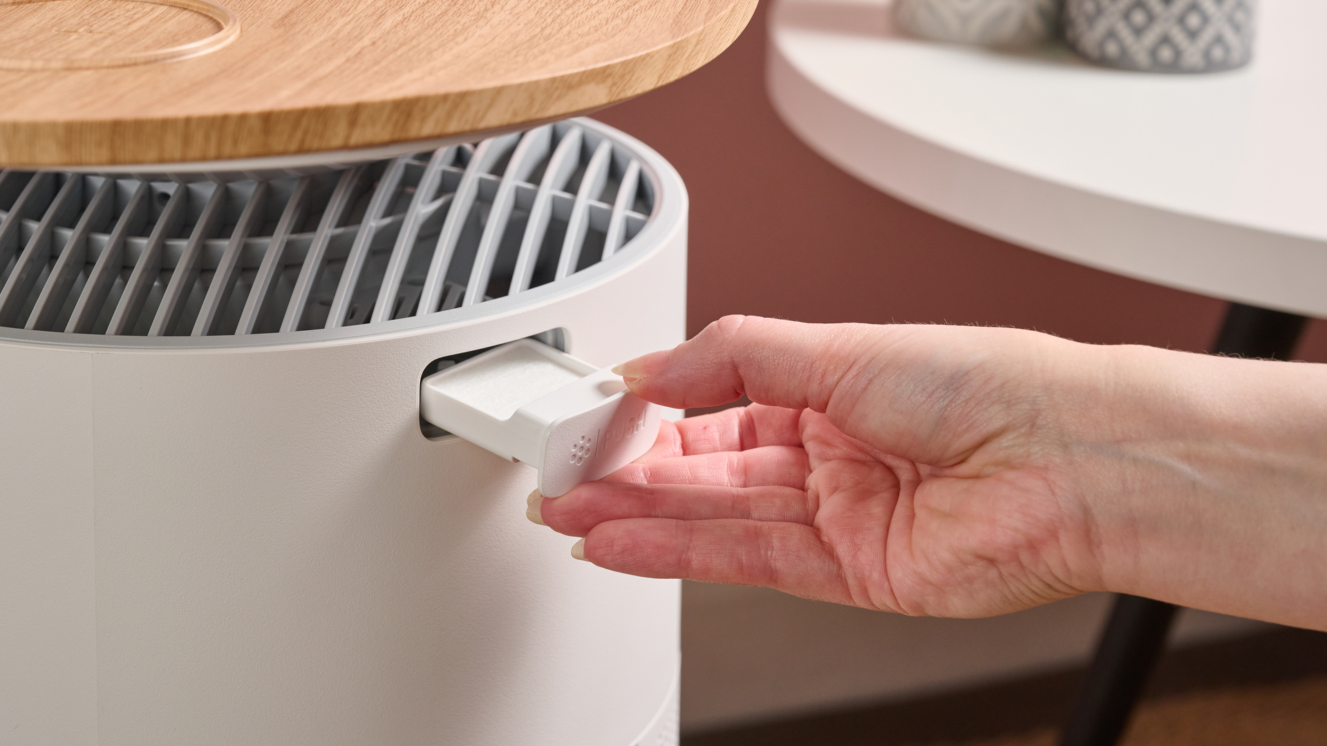 A woman is pulling out the fragrance pad from the side of the air purifier.