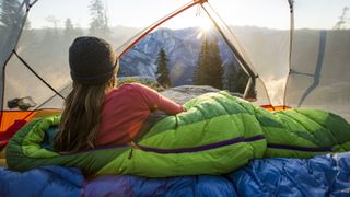 A woman admiring half dome from inside her tent