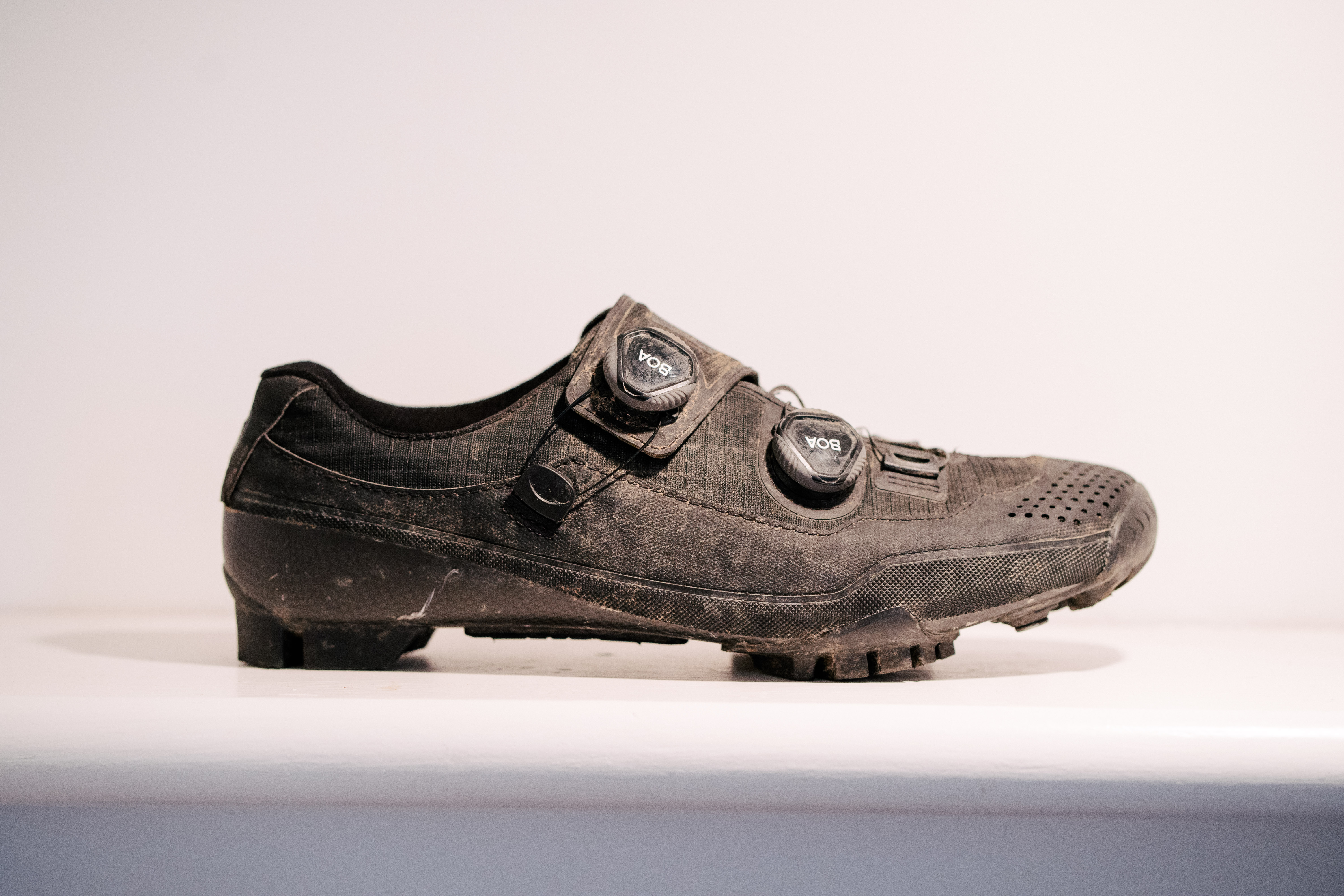 A black, muddy gravel shoe on a white shelf