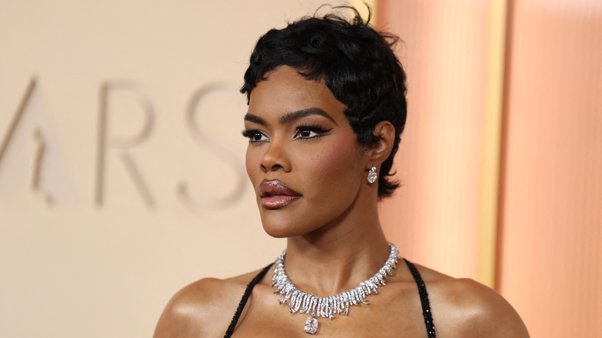 a black woman with short, dark hair poses on the oscars red carpet