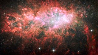 NGC 1569, sparkles with the light from millions of newly formed young stars the cosmic scene glows pink and red.