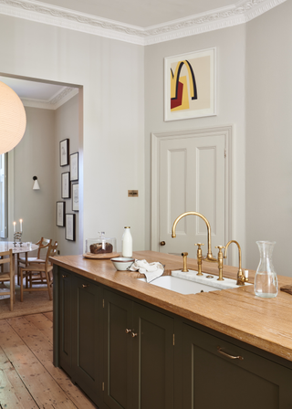 A contemporary classic kitchen design with wooden counters and brass taps