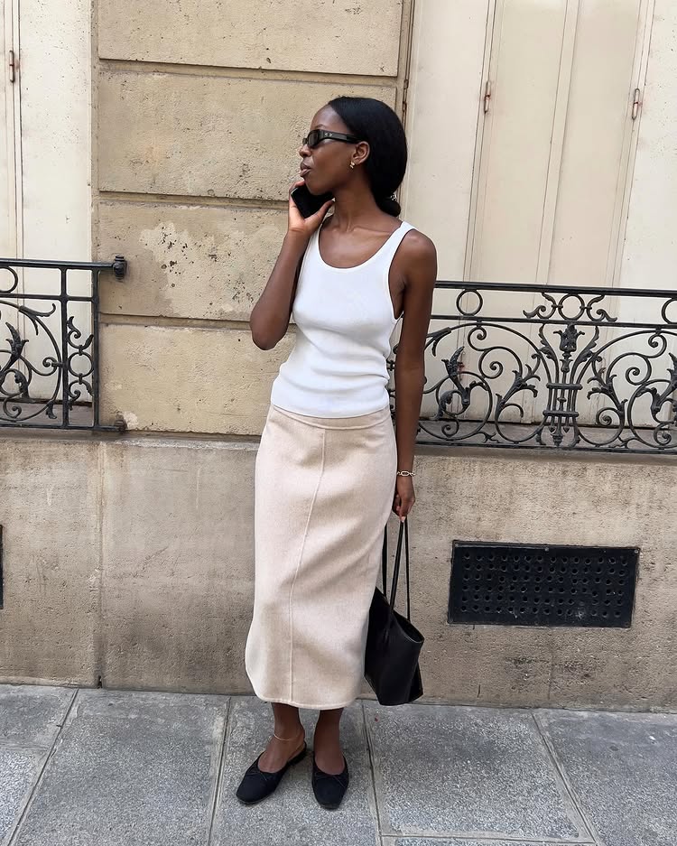 An image of @sylviemus_ wearing a white tank top with pencil skirts.