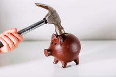 Hand hammers a piggy bank representing crackdown on money market funds in stocks and shares ISA