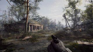 A screenshot from Stalker 2: Heart of Chornobyl, showing the player with their gun raised, looking at a worn-down building from the outside.