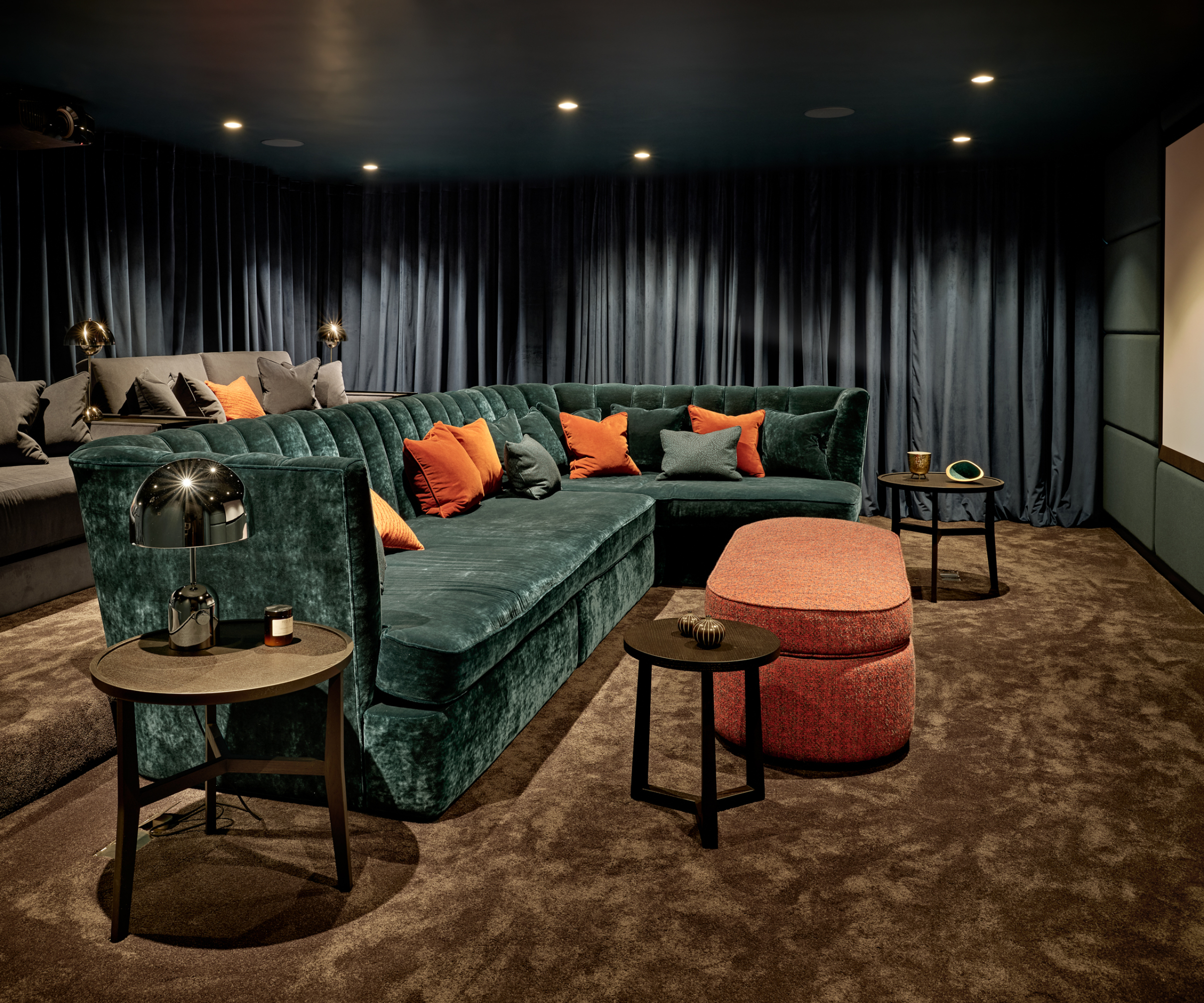 cinema room with two levels of sofa seating in green, grey and orange