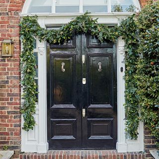 house exterior with brick wall and black door