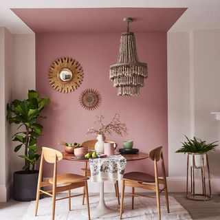 dining room with pink and white wall painting extended to ceiling wooden dinning table with chairs and plant