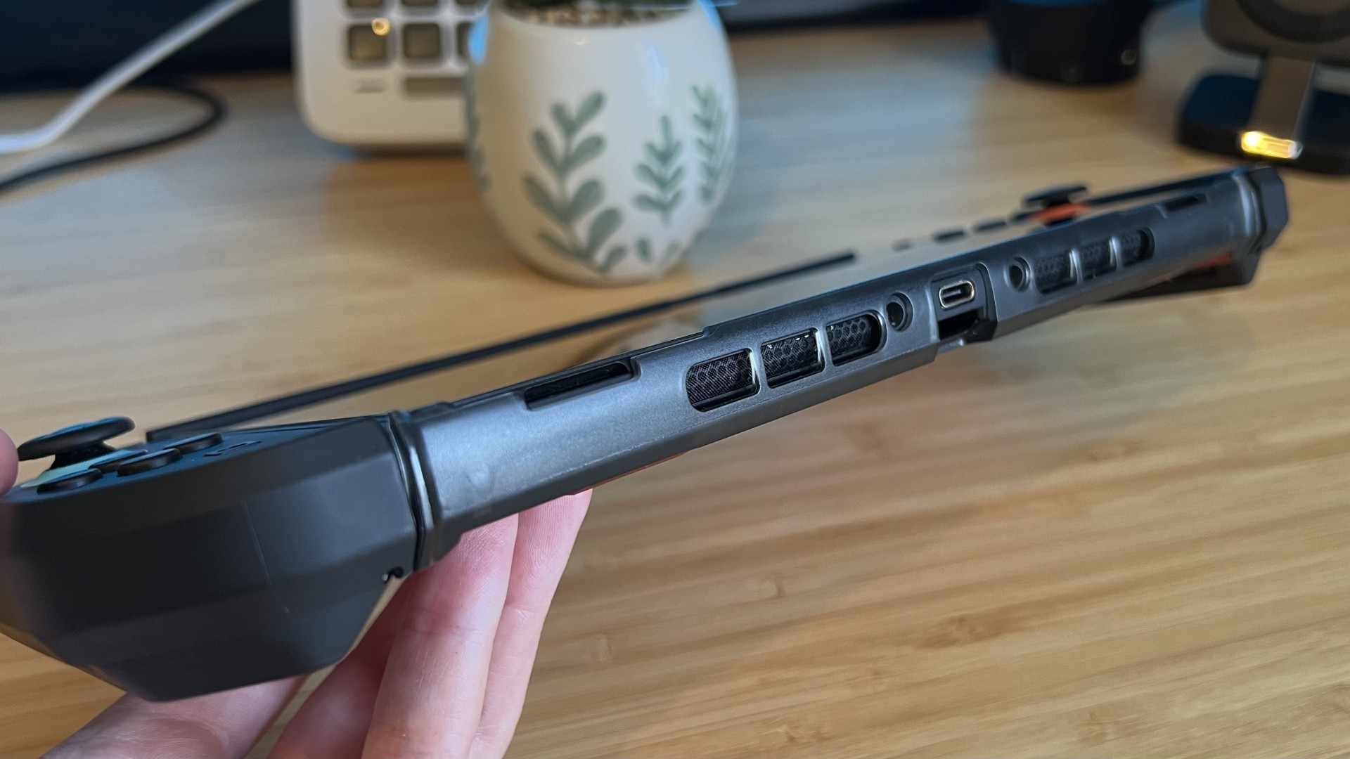 Hand holding a Nintendo Switch 2 with SupCase Unicorn Beetle Pro case applied, angling the handheld with the bottom lip upwards