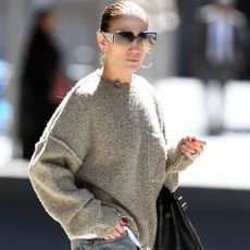 Jennifer Lopez walking on the streets of New York City wearing oversized sunglasses, a slouchy sweater, baggy dirty wash Acne jeans, and tan R13 double stack lace-up boots