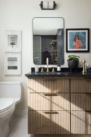 Bathroom with black marble-topped ribbed oak vanity, rectangular mirror showing black metro tiles in shower
