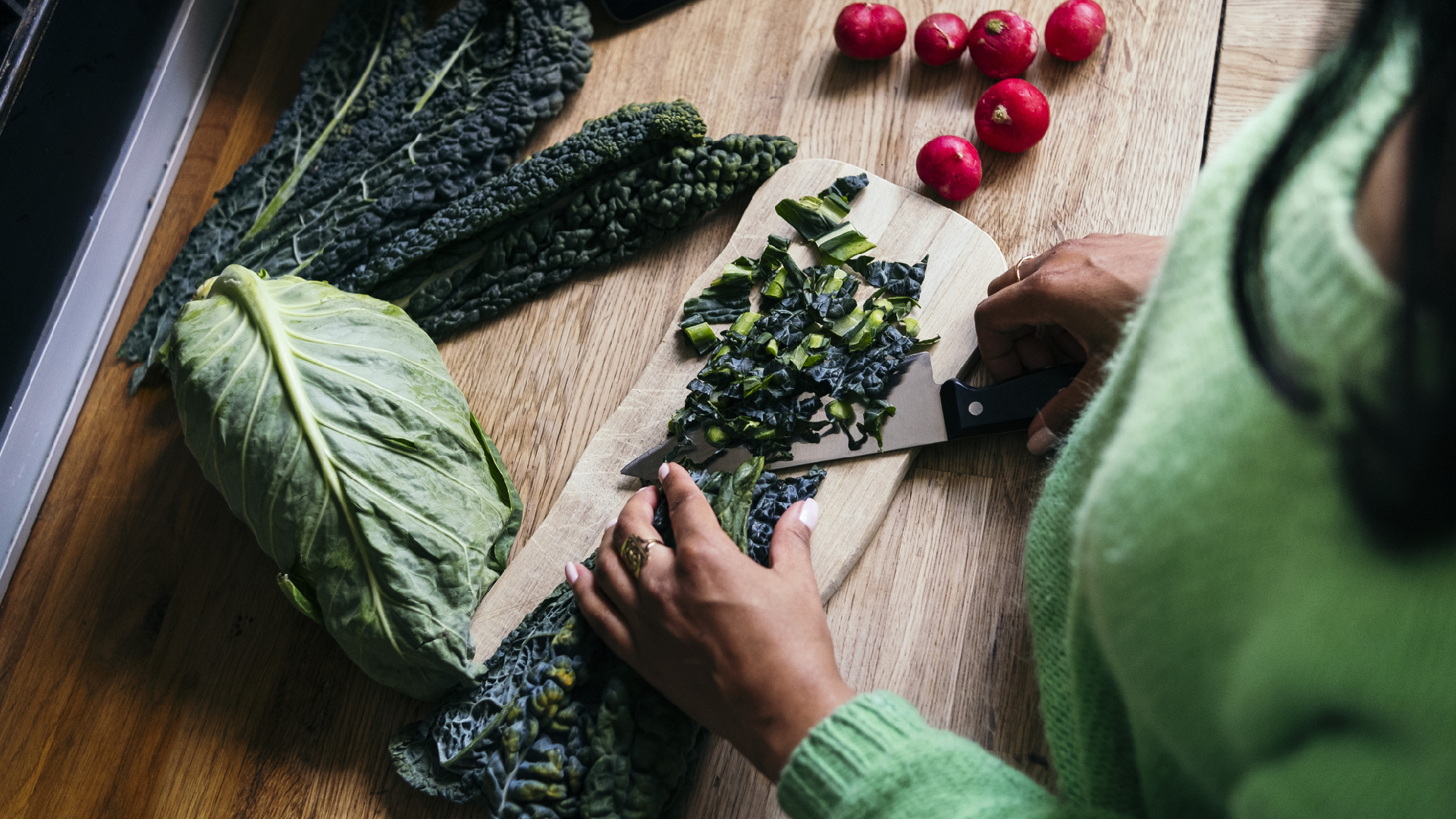 woman chopping kale on a board