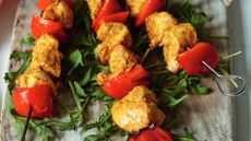 Three skewers of spiced chicken on a bed of rocket