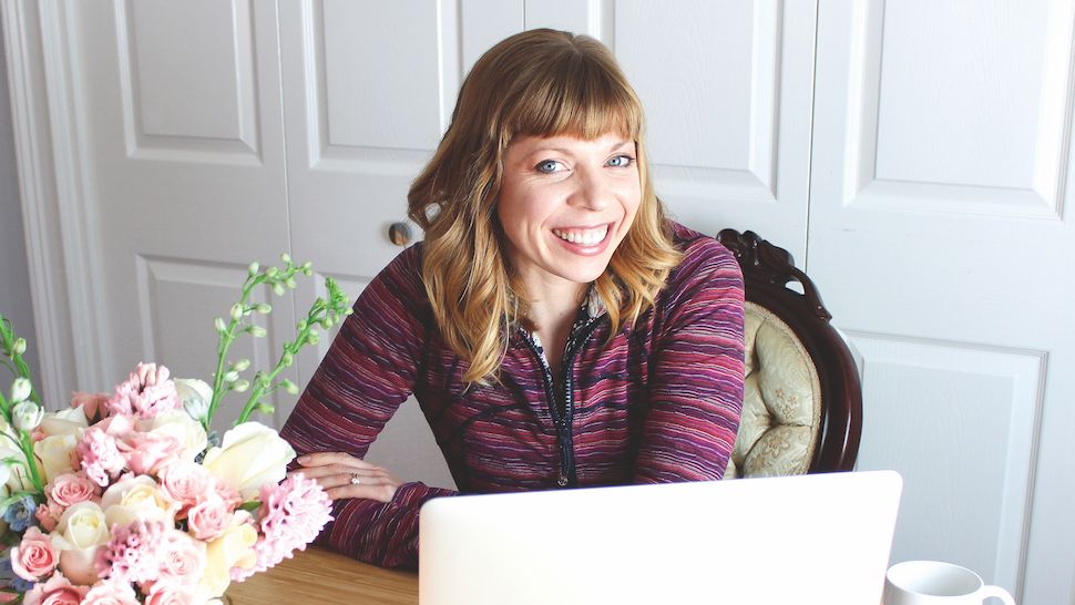 An image of object-oriented UX expert Sophia V Prater – she&#039;s sat at a desk and smiling.