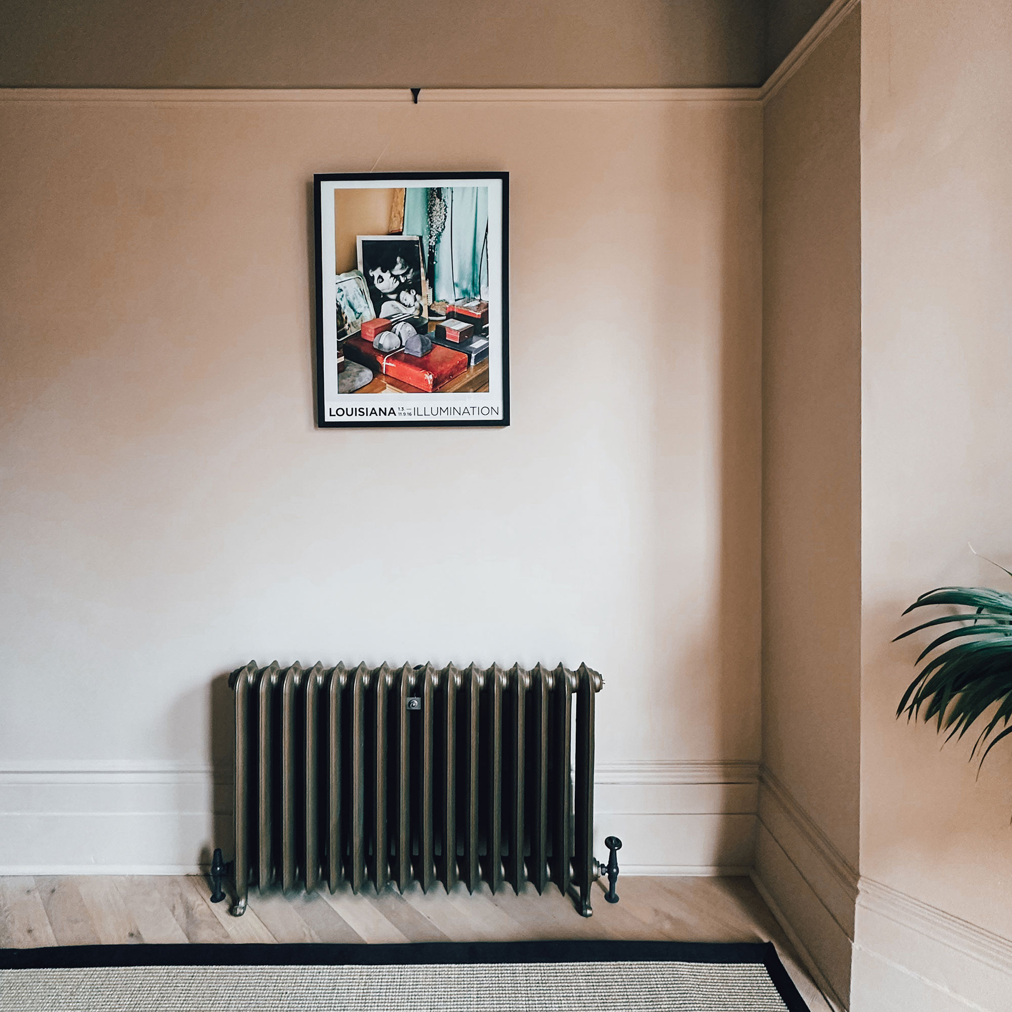 Cast iron radiator against neutral wall with framed art print