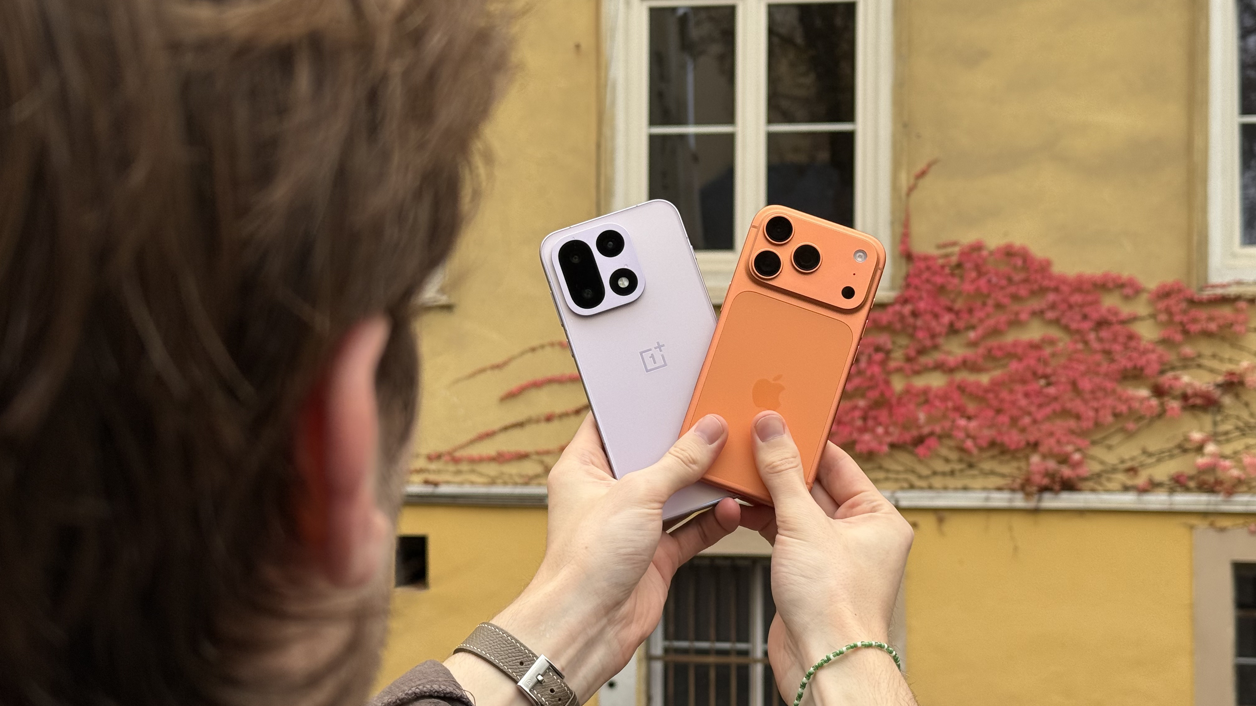 The OnePlus 15 being held up next to the iPhone 17 Pro