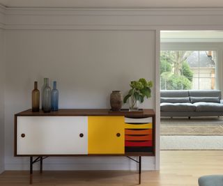 natural wood floor and bright colored cabinet with view to gray sofas