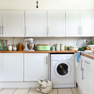 white kitchen cabinets and wooden worktops in kitchen with washing machine